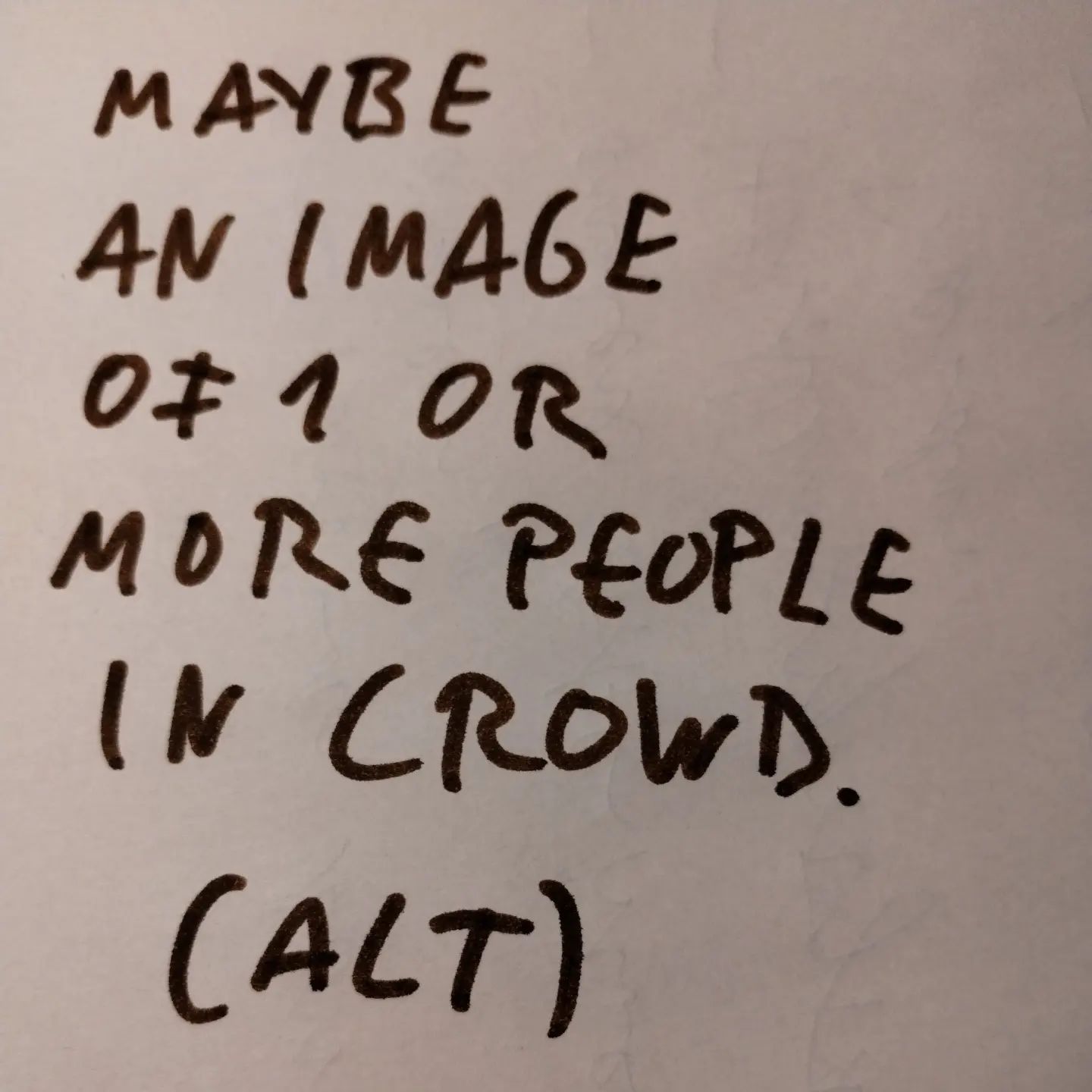 Photo of handwritten text on paper:	Maybe an image of 1 or more people in crowd.	(ALT)